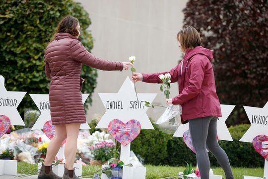 Two women place flowers outside of the Tree of Life Congregation Synagogue